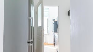 A narrow hallway leading to a kitchen with white cabinets and a window. - 3BR Apt 15 Min from Landstraße Hub (Vienna)