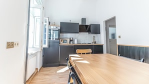 A modern kitchen with a wooden dining table, black cabinets, and a built-in oven. - 3BR Apt 15 Min from Landstraße Hub (Vienna)