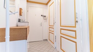 A hallway with white doors, a wooden counter, and a security camera. - 3BR Apt 15 Min from Landstraße Hub (Vienna)