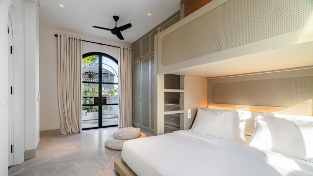 A modern hotel room with a bed, a ceiling fan, a large window with curtains, and a view of the outdoors. - Casa Contenta Canggu (Canggu)