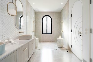 A modern bathroom with a large arched window, a freestanding bathtub, and a round sink. - Casa Contenta Canggu (Canggu)