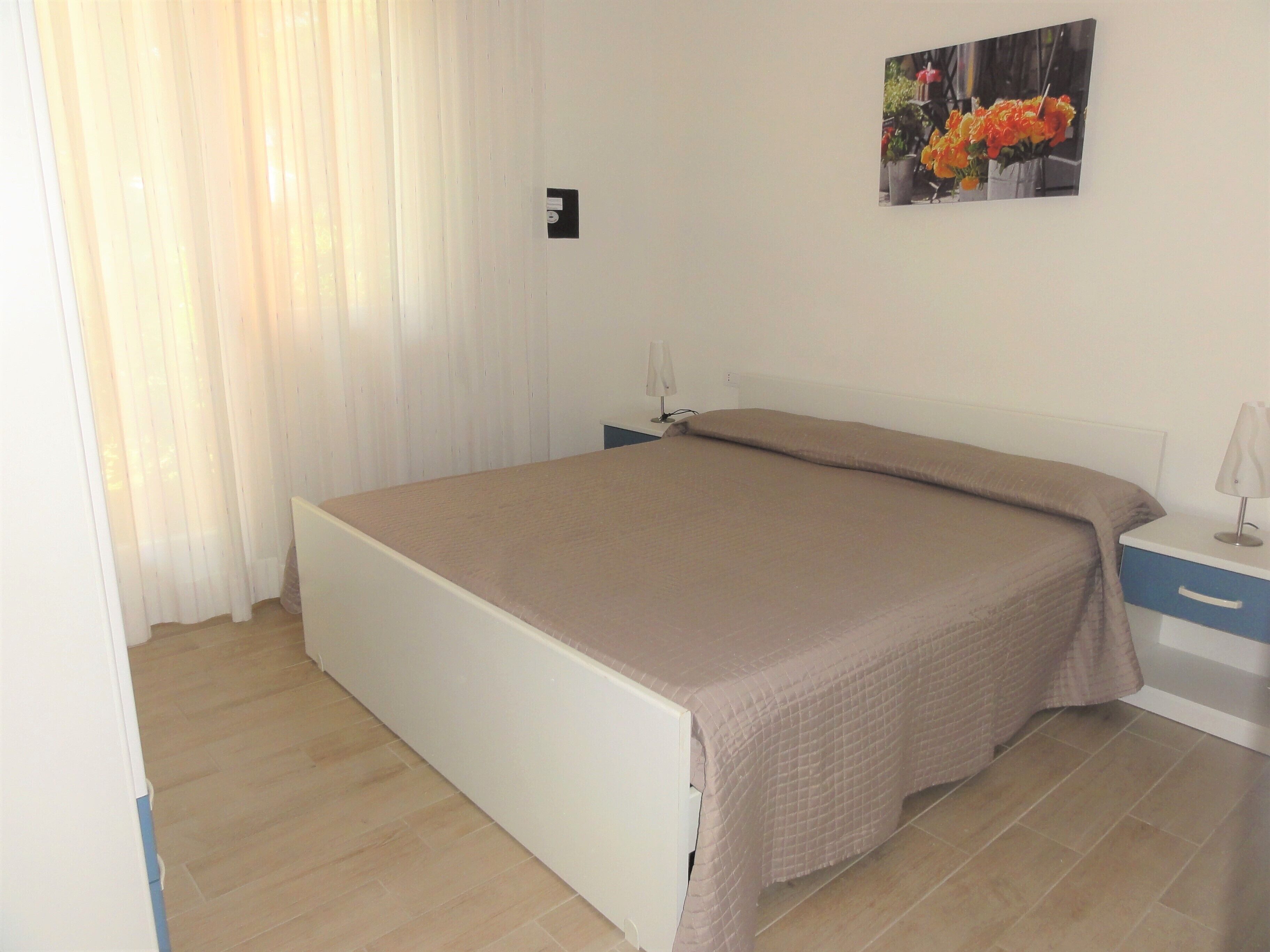 A bedroom with a bed, a nightstand, a lamp, and a picture on the wall.