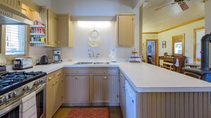 Una cocina con armarios de madera, una isla grande, una estufa a gas y un ventilador de techo.