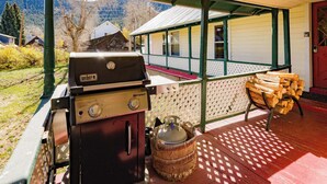 Un espacio al aire libre techado con una parrilla, una cesta de mimbre y una pila de leña.