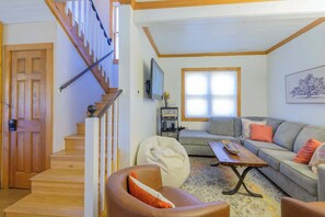 A living room with a staircase, a sofa, a coffee table, and a television. - The Porch House, hot tub, pet friendly, historic! (Crested Butte)