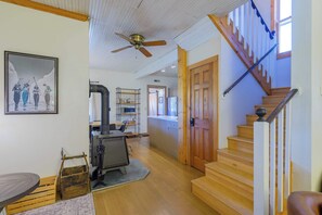 A spacious living area with a wooden staircase, a ceiling fan, and a kitchen area with a grill. - The Porch House, hot tub, pet friendly, historic! (Crested Butte)