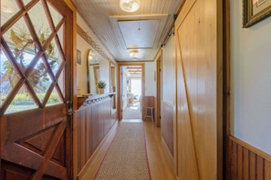 Un couloir en bois avec une porte en verre, un tapis et une plante.