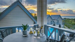 Un balcon avec une table dressée pour deux personnes, une plante en pot et une bouteille de champagne.