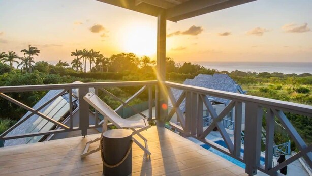 Une terrasse en bois avec une rambarde, un seau et un fauteuil de relaxation.