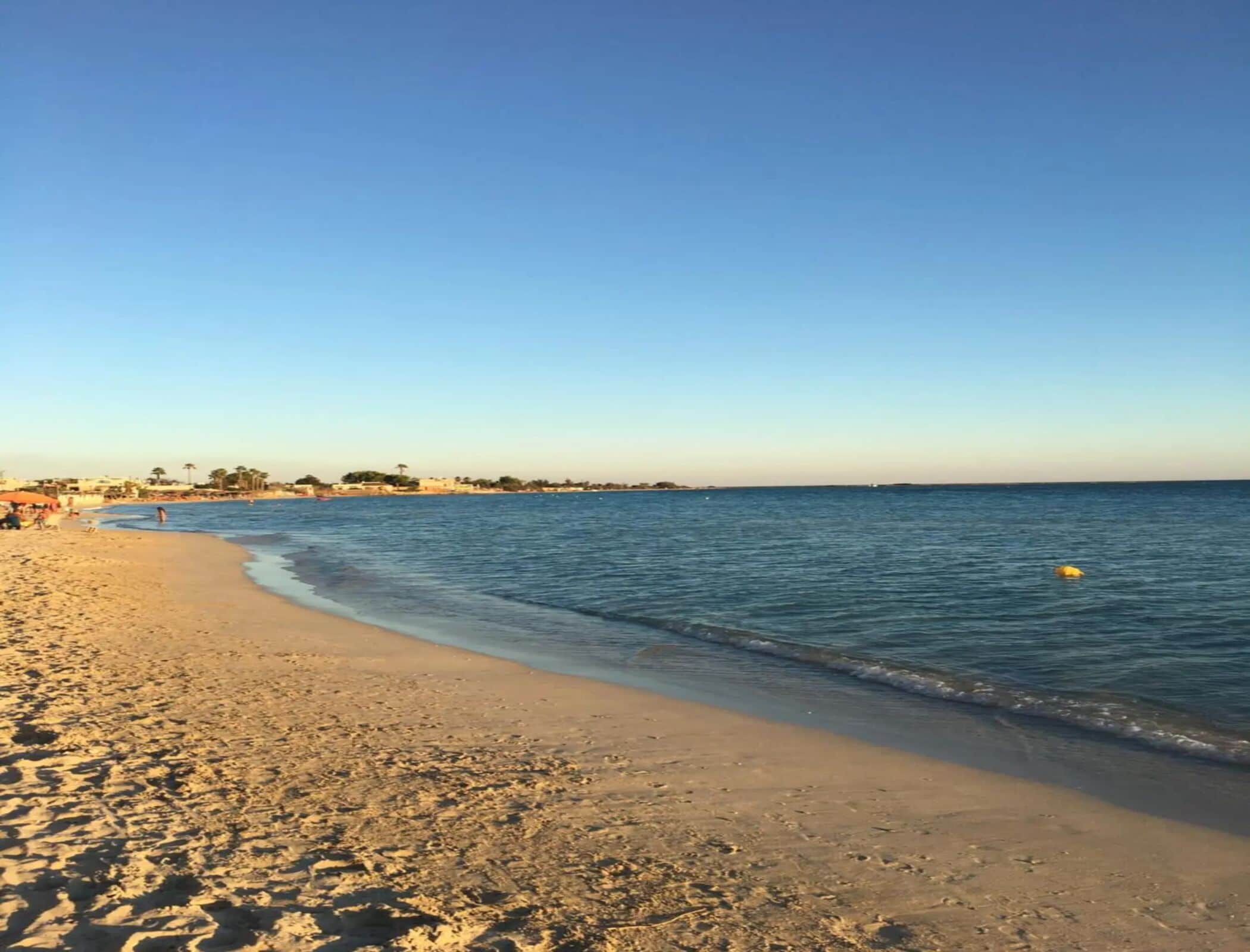 A beach with a sandy shore and calm water.