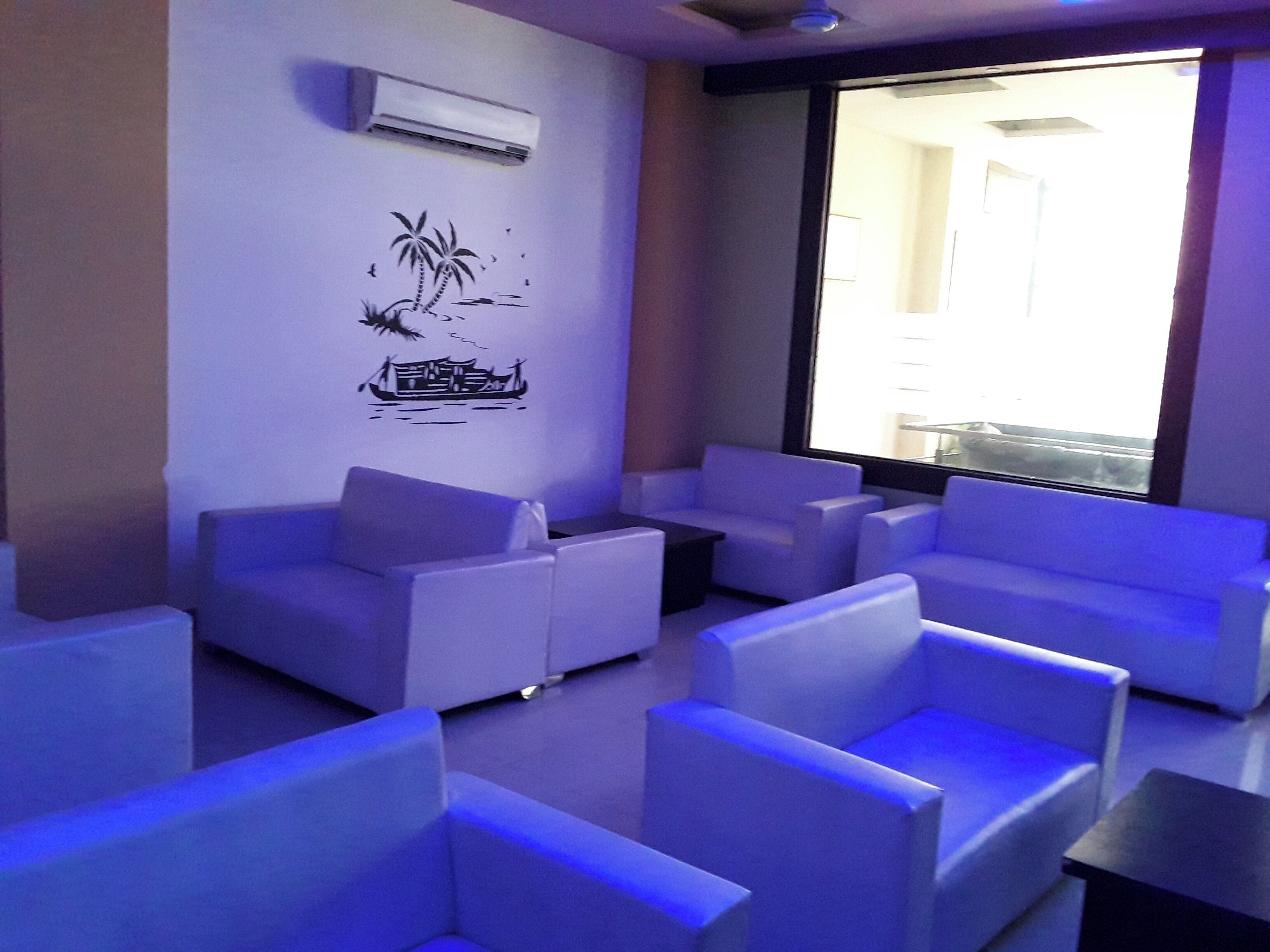 A modern lounge area with white sofas and a wall-mounted air conditioner.