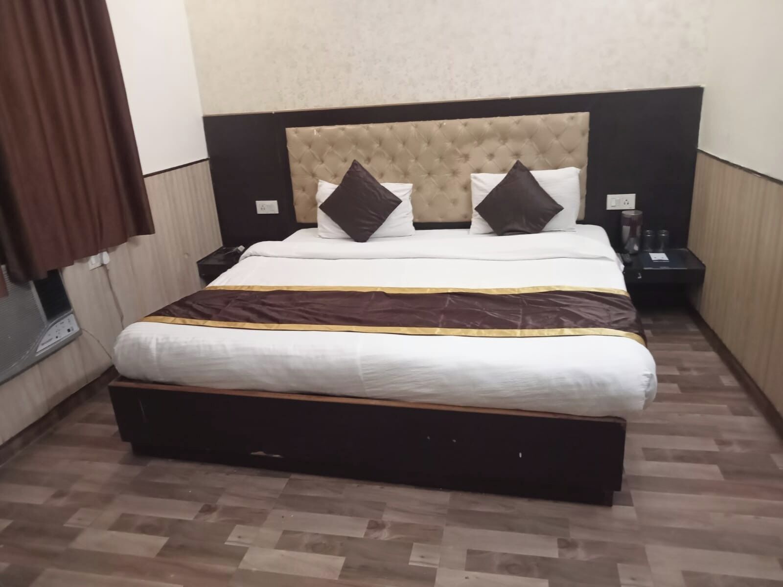 Une chambre d’hôtel avec un grand lit, une tête de lit et une table de chevet équipée d’un téléphone et d’une lampe.