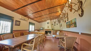 A dining area with a long wooden table, wicker chairs, a fireplace, and wall-mounted antler decorations. - Holiday Home 'Huerta del Sol' with Private Pool, Balcony, and Air Conditioning (Aracena)