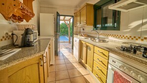 A kitchen with wooden cabinets, a stove, a sink, and a microwave. - Holiday Home 'Huerta del Sol' with Private Pool, Balcony, and Air Conditioning (Aracena)