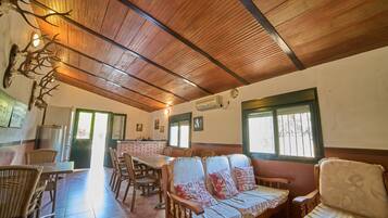 Un comedor con techo de madera, muebles de mimbre y pared de ladrillo.