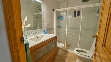 A bathroom with a shower, toilet, sink, and mirror.
