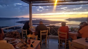 Terraço com vista para o mar e montanhas ao pôr do sol.