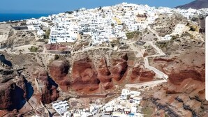 An aerial view of a coastal town with white buildings, a rocky coastline, and several boats anchored in a bay. - Studio Apartment 'Pleasure View 2' with Mountain View, Wi-Fi and Air Conditioning (Perissa)