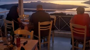 A dining table with chairs, a bottle, and a plate of food. - Studio Apartment 'Pleasure View 2' with Mountain View, Wi-Fi and Air Conditioning (Perissa)