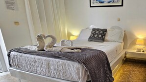 A bed with a heart-shaped towel arrangement, a patterned blanket, and a pillow with a geometric design. - Studio Apartment 'Pleasure View 2' with Mountain View, Wi-Fi and Air Conditioning (Perissa)