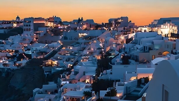 A couple in a heated outdoor jacuzzi with a view of a white-washed town at sunset. - Studio Apartment 'Pleasure View 2' with Mountain View, Wi-Fi and Air Conditioning (Perissa)