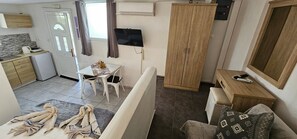 Ein kleines Zimmer mit Küchenzeile, Essbereich, Fernseher und Kleiderschrank.