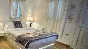 Un lit bien fait, avec une couverture, une lampe et des serviettes décoratives en forme de cygne posées sur le lit.