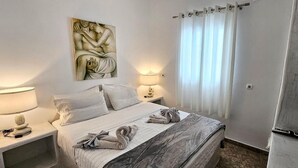 Een hotelkamer met een bed, twee bedlampen, een schilderij, een televisie en een gordijn.