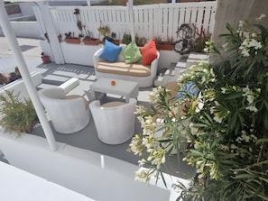 A patio with outdoor furniture, potted plants, and a white fence. - Studio Apartment 'Pleasure View 2 Persons 3' with Mountain View, Wi-Fi and Air Conditioning (Perissa)