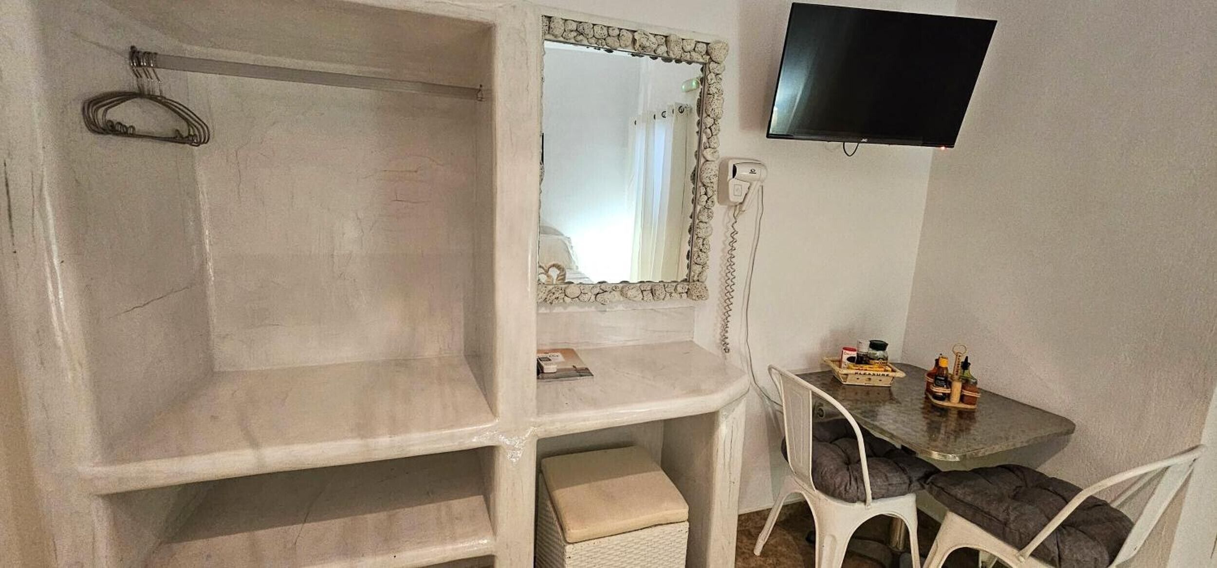 Un bagno con doccia, uno specchio, una televisione e un tavolino con articoli da toilette.