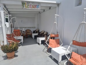 A covered outdoor seating area with white wicker furniture, orange cushions, and a potted plant. - Studio Apartment 'Pleasure View 1  Persons 3' with Mountain View, Wi-Fi and Air Conditioning (Perissa)