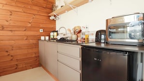 A modern kitchen with wooden paneling, a built-in dishwasher, a toaster, and a kettle. - Teach Tra West (Perranporth)