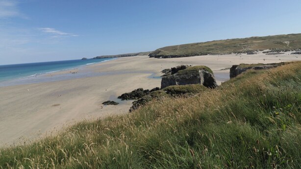 A coastal beach with clear skies, sandy shores, and grassy dunes. - Teach Tra West (Perranporth)