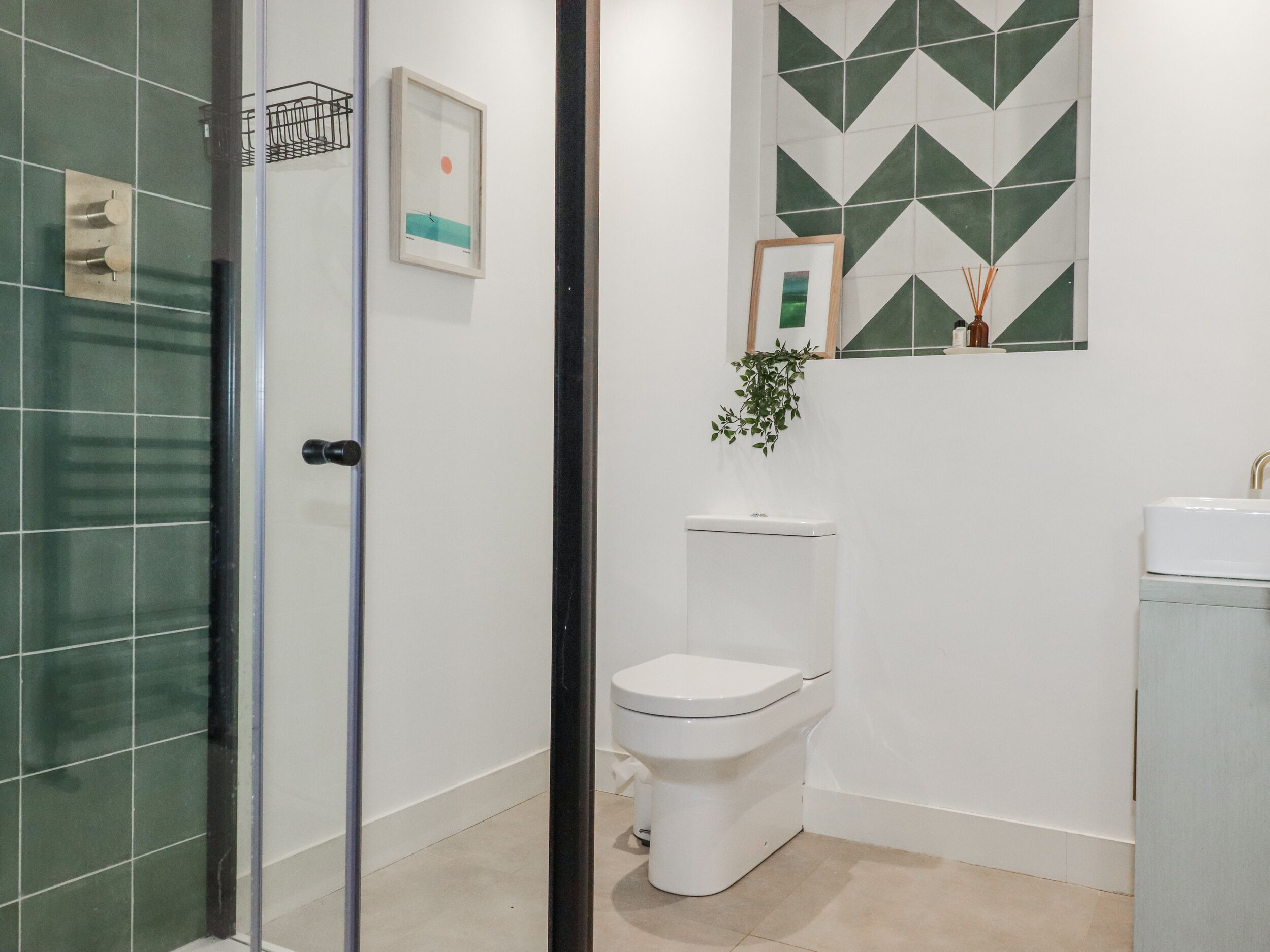 Een badkamer met een glazen douchecabine, toilet en wastafel.