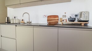 Una cocina moderna con un lavamanos de acero inoxidable, una tabla de cortar de madera, un tostador y una cafetera.