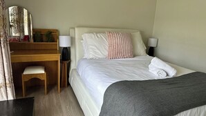 Ett hotellrum med en säng, ett skrivbord, en stol och en spegel.