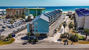 A hotel with a blue building, a parking lot, and a view of the ocean. - Romar Beach 208 Steps from the Gulf! (Orange Beach)