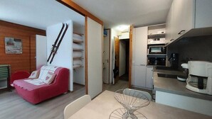 Ein kompakter Wohnbereich mit Küchenzeile, Essplatz und einem roten Sofa.