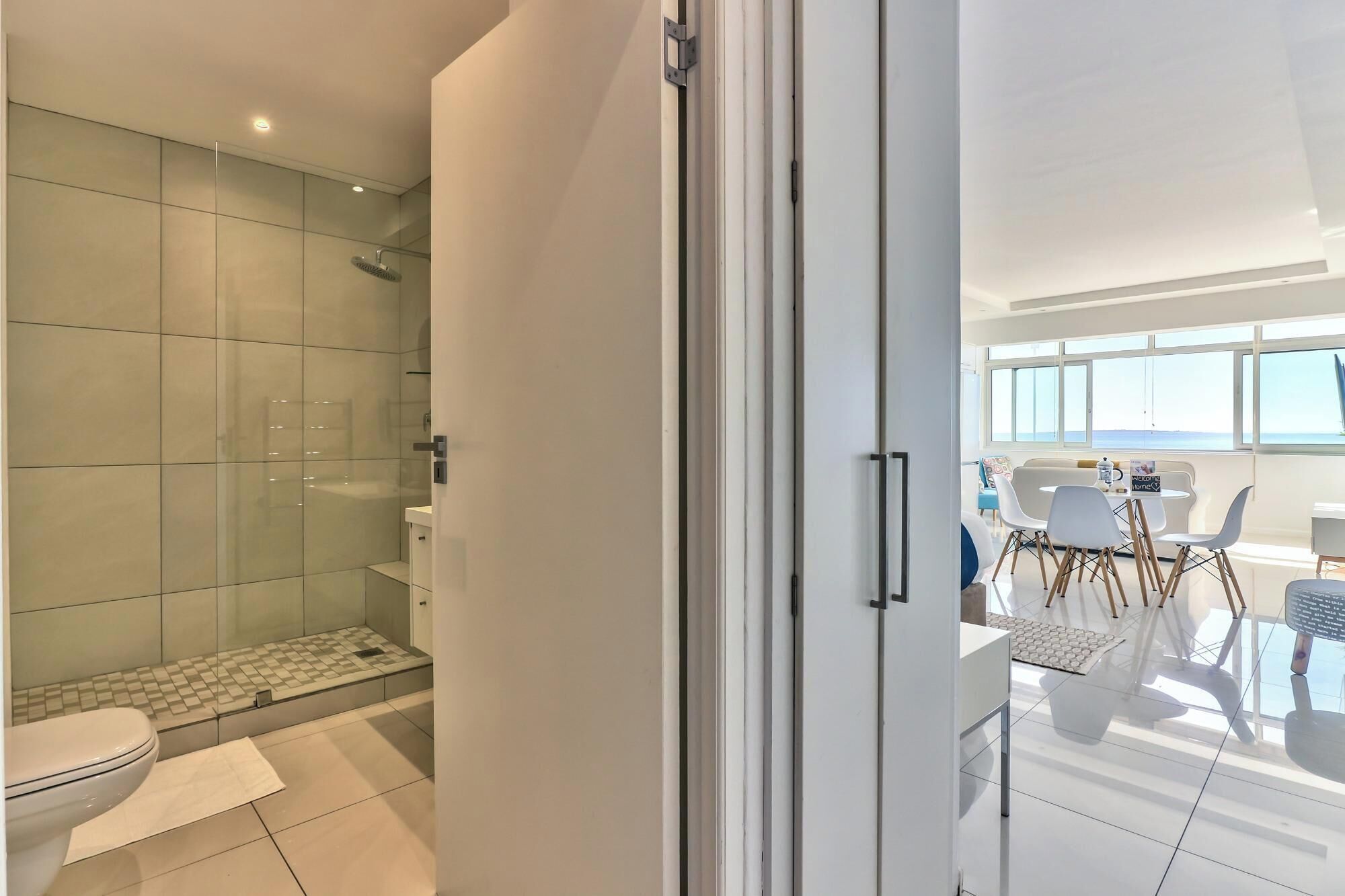 A modern bathroom with a glass shower enclosure, a toilet, and a sink.