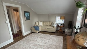 A spacious loft bedroom with a large window, a ceiling light, a wooden dresser, and a globe. - Cozy 1-bed, 1-bath apartment in Geneva, NY, steps from downtown & Seneca Lake! (Geneva)