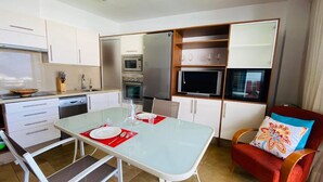 Cocina compacta con armarios blancos, microondas y horno empotrado.