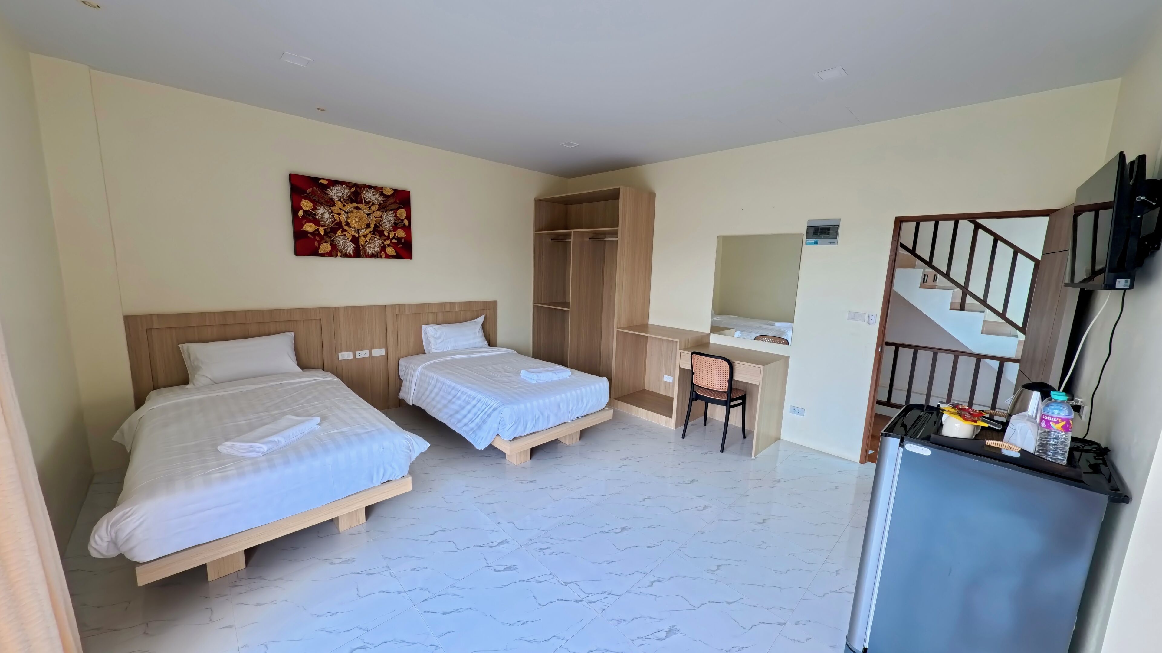 Une chambre d’hôtel avec deux lits, un bureau, une chaise, une armoire et un téléviseur.