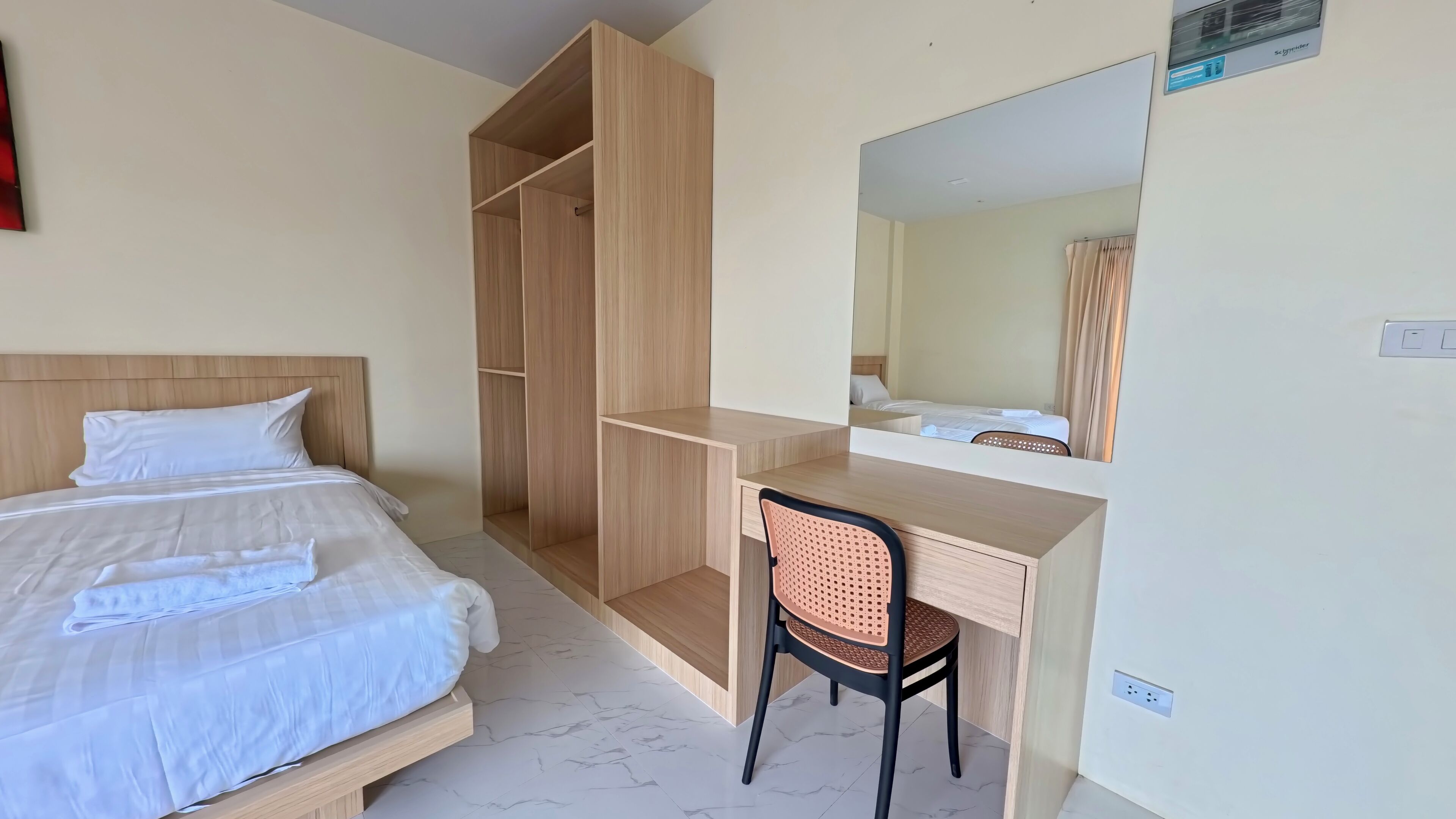 A hotel room with a bed, a desk, a chair, and a wardrobe.
