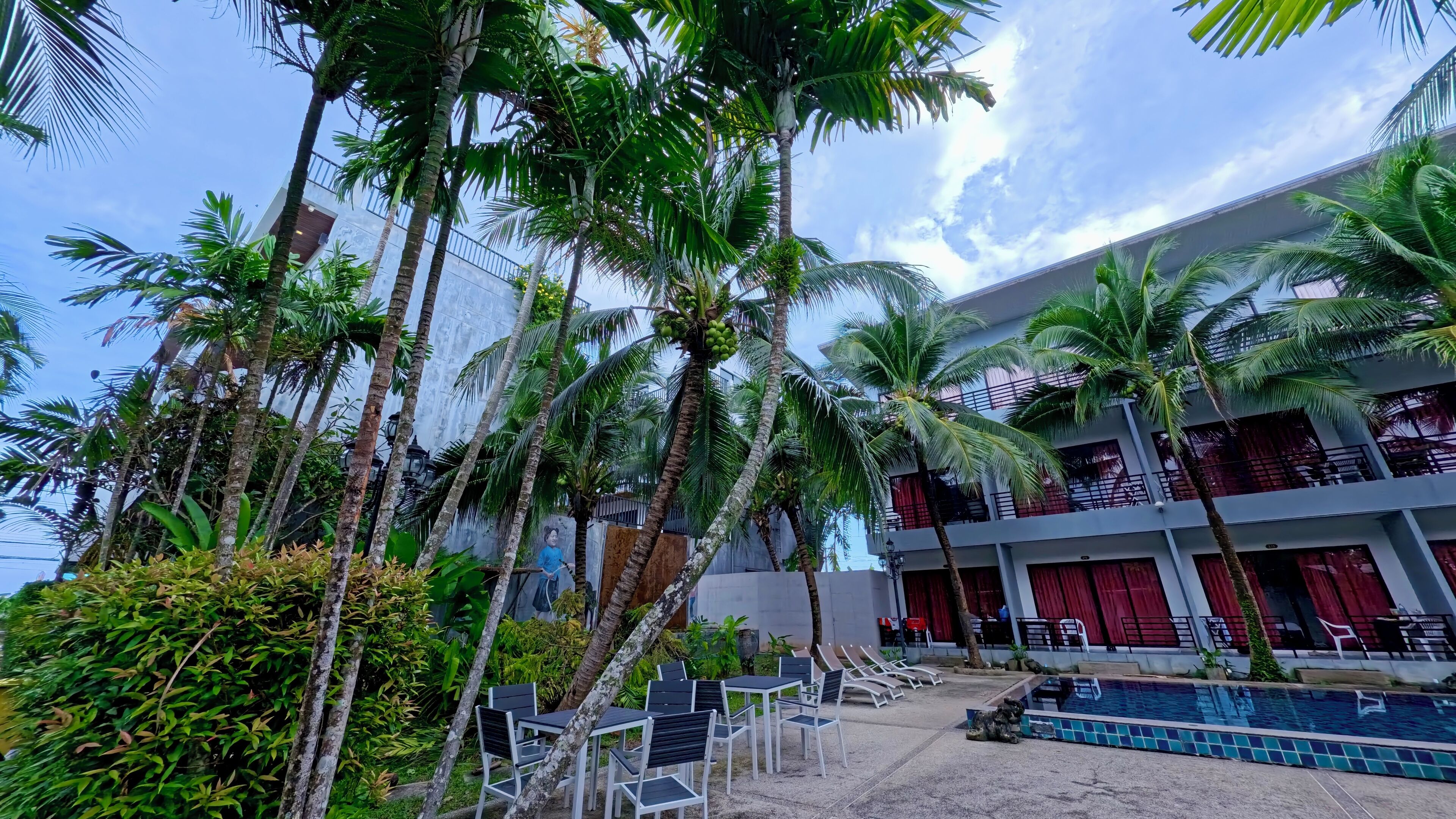 A hotel with a pool, outdoor seating, and palm trees.