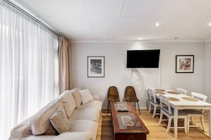 A living room with a sofa, a coffee table, a TV, and a dining area with chairs and a table. - Stylish Apartment in Prime Location with Wi-Fi (Nürnberg)