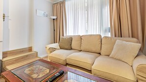 Un soggiorno con un divano color beige, un tavolino in vetro, una lampada e un quadro incorniciato appeso al muro.