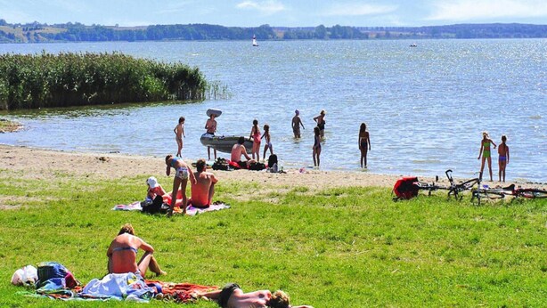 A lakeside beach with people sunbathing and swimming. - Cottages at the Kummerower See in Verchen (Verchen)