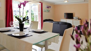A dining area with a table set for four, a sofa, and a TV in the background. - Cottages at the Kummerower See in Verchen (Verchen)