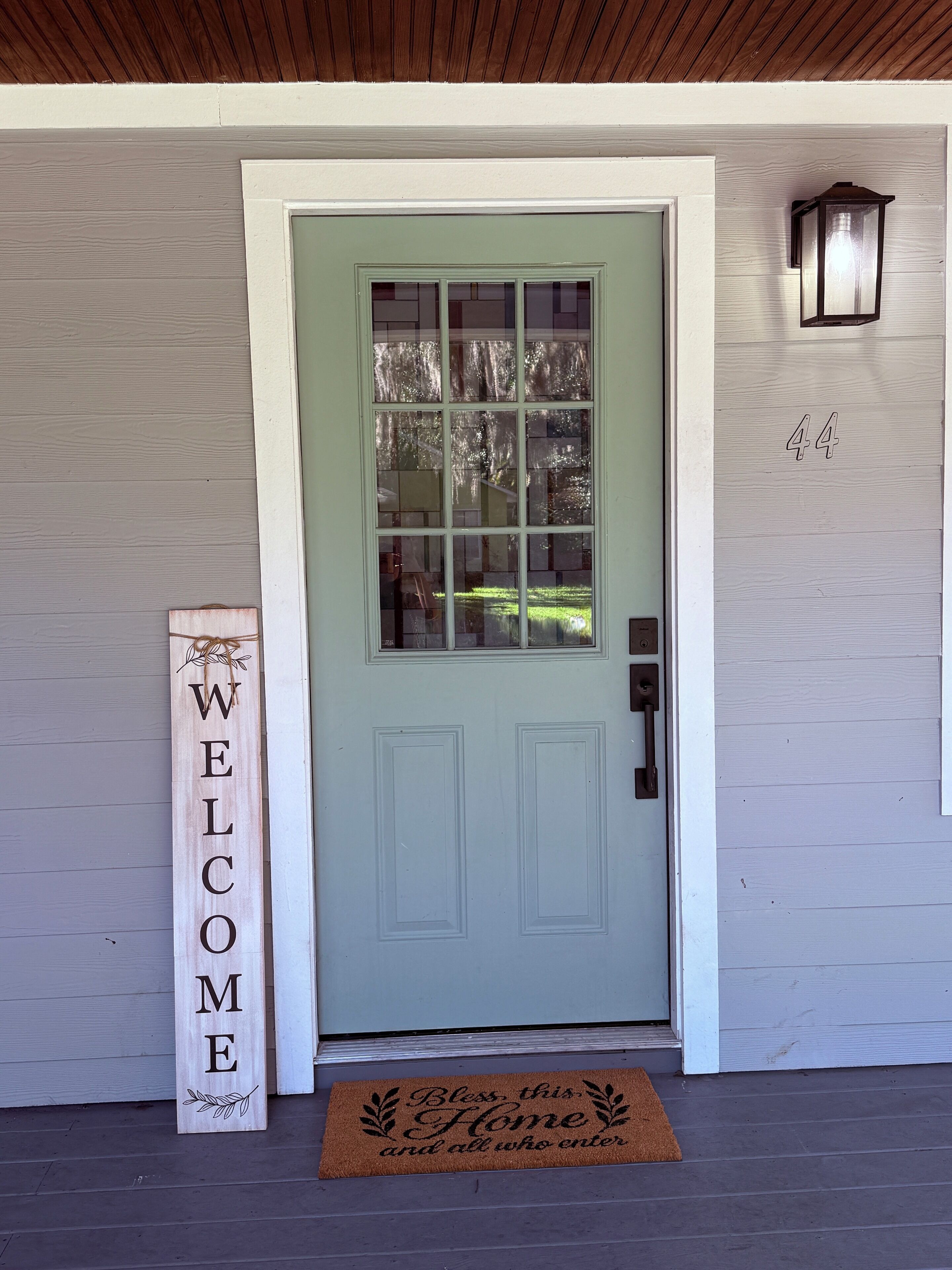 Une porte d’entrée avec une pancarte indiquant « BIENVENUE », une boîte aux lettres et le numéro de la maison, qui est le 44.
