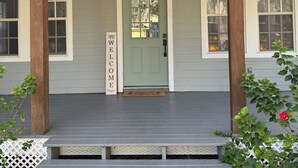 A house with a green door, a welcome sign, and a porch with steps. - Charming 3-bedroom house in enchanting St. Augustine with AC (St. Augustine)